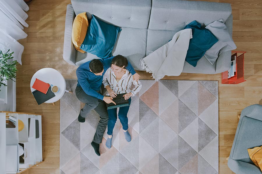 Client Center - Couple Using a Laptop on the Floor of Their Colorful Living Room, Seen From Above